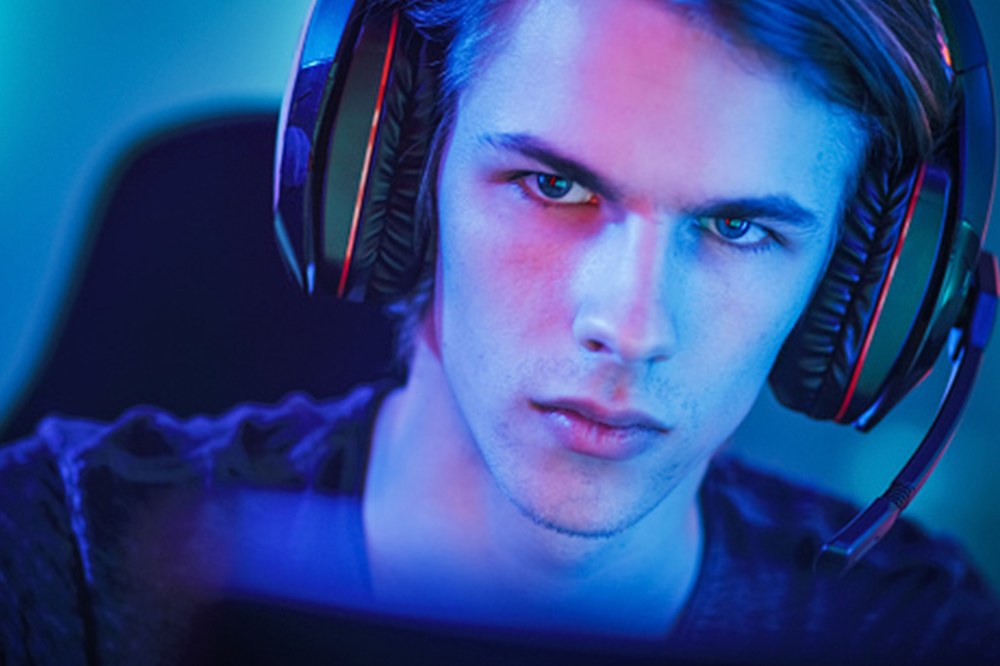 Chico con cascos inalámbricos gaming con micrófono, con unos cascos con lineas rojas.